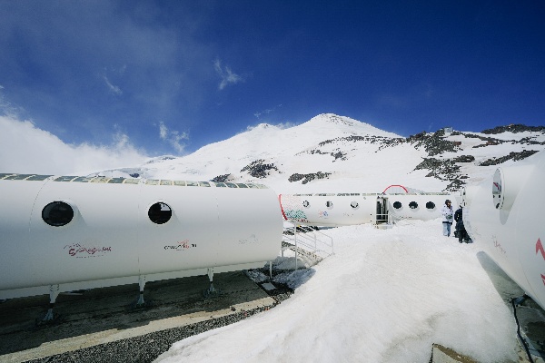 Самый высокогорный отель на Эльбрусе будет работать под брендом Космос.

Ведущий гостиничный оператор России Сosmos Hotel Group и институт развития Кавказ.РФ подписали соглашение по совместному развитию гостиничного сервиса для альпинистов на курорте «Эльбрус» в Кабардино-Балкарии. Первым этапом сотрудничества стал переход действующего высокогорного отеля-приюта Leaprus на высоте 3 912 метров над уровнем моря под бренд и франшизу Cosmos, что гарантирует работу по стандартам сервиса и качества федерального оператора.

С началом нового альпинистского сезона 2026, который традиционного проходит с апреля по сентябрь, эко-отель LeapRus откроется под названием Cosmos Elbrus Leaprus Camp. Его уже можно забронировать на сайте Cosmos Hotel Group на период проживания с апреля по сентябрь 2026 года. Кроме того, объект появится в программе лояльности Cosmos Stars, что позволит участникам программы оплачивать проживание накопленными баллами. 

Эко-отель был построен в 2013 году и находится на высоте 3 912 метров над уровнем моря рядом со станцией канатной дороги «Гарабаши» курорта «Эльбрус», ближайший населенный пункт – село Терскол. Служба приема и размещения отеля располагается на поляне Азау, рядом с кассами на канатную дорогу. 

Объект стал центром акклиматизации и отдыха для профессиональных альпинистов и тех, кто выбирает активный или экологический туризм на вершине Эльбрус. Для комфортного размещения отель предлагает суммарно 34 спальных места в модулях с системой отопления, горячей водой и душем, гардеробной зоной и большим панорамным окном с видом на вершины Кавказских гор. На территории отеля работает wi-fi, есть кафе-столовая и помещение для сушки экипировки и снаряжения. В ночное время территория отеля освещается и оборудована системой сигнальных огней. 

«Для нас – это знаковый проект и первый самый высокогорный отель в Европе под нашим брендом. Для нас важно создавать и развивать качественный гостиничный сервис для самых разных категорий гостей, и экстремальные туристы и альпинисты не исключение. Уверен, что совместный опыт и экспертиза Cosmos Hotel Group и института развития Кавказ.рф создадут комфортный отдых для тех, кто покоряет вершину Эльбрус со всего мира», – отметил президент Cosmos Hotel Group Александр Биба. 

«Все проекты, которые связаны с высокогорьем Эльбруса, по умолчанию становятся "самыми" в стране: в первую очередь самыми сложными технически и логистически. Продолжаем сейчас строить инфраструктуру для восхождений: возводим альпгородок на 68 мест и готовимся выйти на стройку "Приюта одиннадцати", поэтому опыт построения высокогорного отельного сервиса в ближайшие годы будет как никогда востребован. Кроме того, работа на горе – это трансформирующий опыт сродни восхождениям: кто справится с вызовами здесь, сможет достичь любых высот на равнине. Поэтому уверен, что опыт работы с Leaprus так или иначе повлияет на работу Сosmos Hotel Group в целом», – сказал генеральный директор Кавказ.РФ Андрей Юмшанов. 

Ранее, на Кавказском инвестиционном форуме Сosmos Hotel Group и институт развития Кавказ.РФ подписали соглашение о совместном развитии туризма и подготовке кадров для индустрии гостеприимства в регионах Северного Кавказа. 

Эльбрус – легендарный и самый высокогорный курорт страны, который делает доступной гостям высоту 3847 метров над уровнем моря. Работает с 70-х годов прошлого века и неизменно остается одним из главных центров горнолыжного отдыха, спорта, альпинизма в стране. Модернизация курорта идет под управлением Кавказ.РФ:  в новом сезоне расширена зона катания и запущена система оснежения, которая позволит продлить и без того самый продолжительный горнолыжный сезон в России – с ноября по июль. 

LeapRus – один из самых высокогорных отелей мира, современная акклиматизационная база для альпинистов, которая отличается необычным для высоты 3912 метров комфортом: есть электричество, горячая вода, интернет, сушильные камеры. В кают-компании можно приготовить еду самостоятельно или питаться в формате шведского стола. Два жилых модуля рассчитаны на 24 гостя. 

Гостиница построена итальянской компанией Leapfactory по заказу Северо-Кавказского горного клуба. Технология рекуперации тепла, светодиодное освещение, теплоизоляционные и антибактериальные свойства материалов – всё служит максимальной автономности, энергоэффективности и экологичности комплекса. Разборные элементы капсул, которые монтировали на фундамент с помощью вертолетов, обеспечивают сейсмоустойчивость всех конструкций. 

Архитектура гостиничного комплекса – обтекаемый дизайн, иллюминаторы, панорамное остекление, геометричность – отсылает к стилистике ретрофутуризма и модернизму середины века. 

Cosmos Hotel Group – ведущий федеральный гостиничный оператор России, бренд которого создан в 2018 году. В портфель компании входит 44 отеля исключительно категорий от 3* (городские отели) до 5* (отели премиум-класса, в том числе и курортные комплексы) в 28 городах России. Компания осуществляет операционное управление активами с номерным фондом более 11,5 тыс. единиц.
